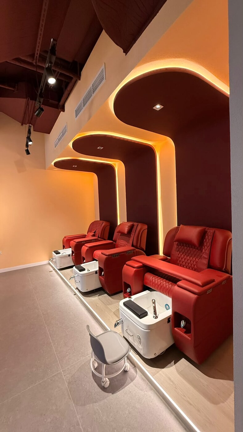 Red leather pedicure thrones in backlit burgundy alcoves at our Business Bay salon