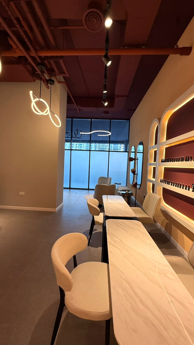 Marble manicure bar with boucle chairs and a backlit polish wall
